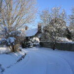Guys cottage on a snowy day with blue sky and road way
