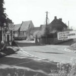 Black and white photo of corner of old School House with the sign post to Dorchester, Chilton Hampden and Abington pointing to the left